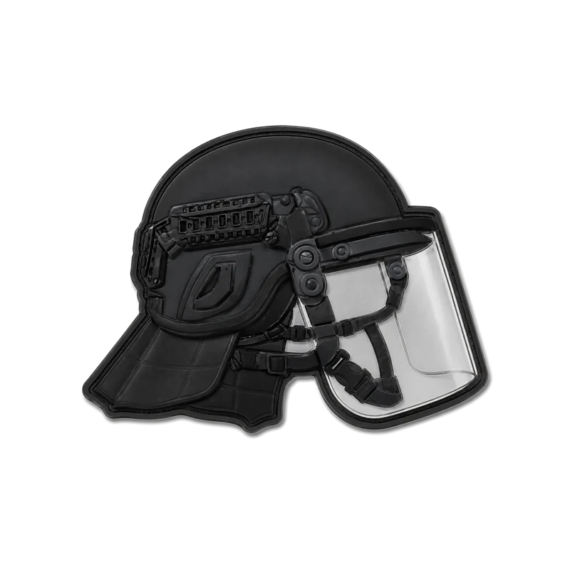 Écusson découpé à la forme d’un casque noir à visière transparente, vu de profil.
